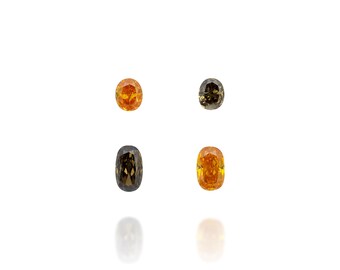 Puede incluir: Cuatro gemas ovaladas en tonos naranja y marrón. Las gemas se muestran sobre un fondo blanco, con reflejos visibles debajo. Las gemas varían en color, desde naranja claro hasta marrón oscuro.