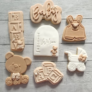 Pode incluir: Um conjunto de nove biscoitos de a&ccedil;&uacute;car decorados para um ch&aacute; de beb&ecirc;. Os biscoitos s&atilde;o decorados com ursinhos de pel&uacute;cia, blocos, um carrinho de beb&ecirc; e as palavras "Baby" e "Bem-vindo beb&ecirc; Wilson".