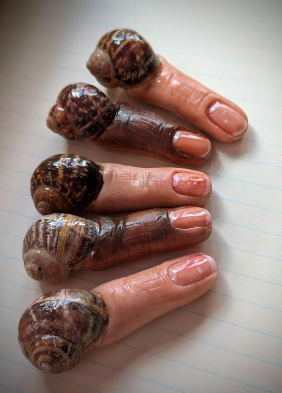 A tiny handcrafted polymer clay monstrosity — part snail, part fingernail, all unsettling — the kind of weird desk creature that makes every visitor ask 'what IS that?'