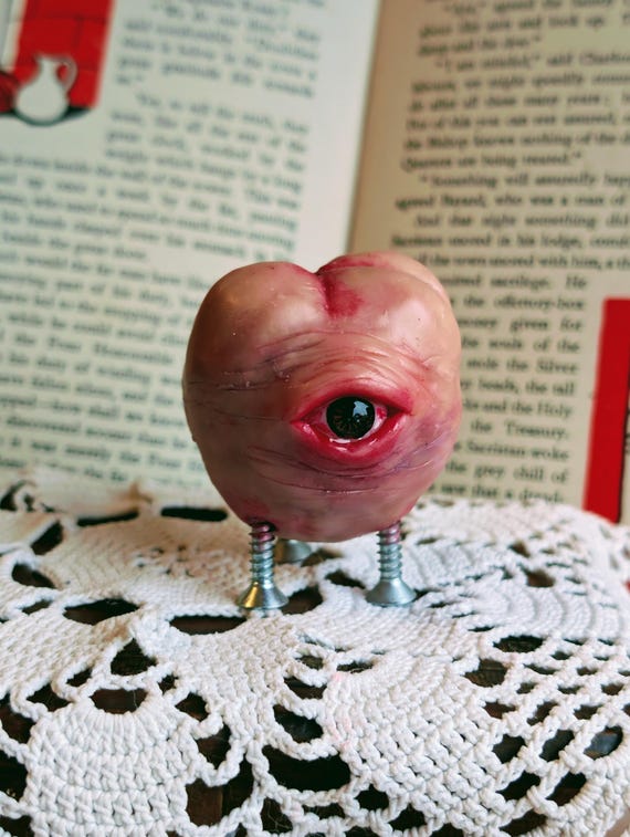 A polymer clay tooth with an eyeball growing out of it — 50 favorites don't lie, this is the desk buddy you didn't know you needed and can't unsee.
