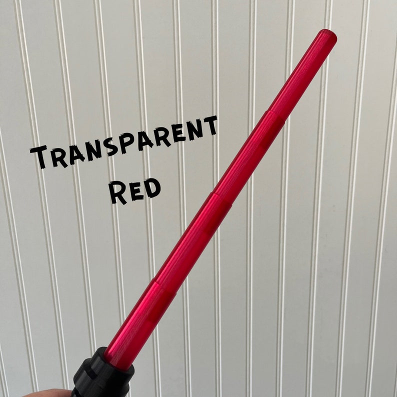 Puede incluir: Un juguete de sable de luz rojo transparente. El sable de luz est&aacute; hecho de pl&aacute;stico y tiene un mango negro.