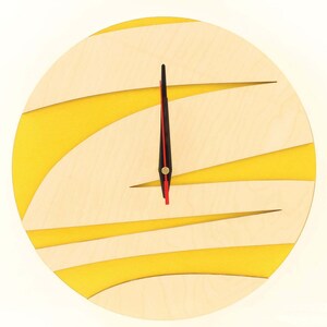 May include: A round wooden clock with yellow stripes and black hands. The clock face is made of light wood with yellow stripes.