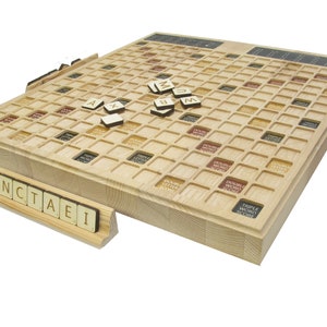 Może przedstawiać: Drewniana plansza do gry w Scrabble z jasnobrązowym wykończeniem. Plansza ma siatkę 15x15 kwadratów z różnymi kolorami kwadratów dla punktów bonusowych. Na planszy i w stojaku znajdują się płytki z literami. Stojak jest drewniany i ma na sobie litery "ZNCTAEI".