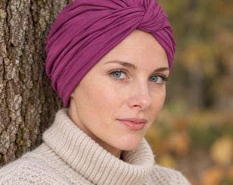 May include: A deep magenta turban-style head covering featuring a gathered, knotted front design with soft, draped fabric folds that wrap around the head, providing full coverage in a solid, vibrant berry-toned color.