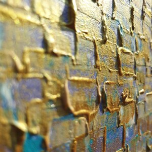 Pode incluir: Close-up de uma pintura abstrata texturizada com tons dourados e azuis. A tinta é aplicada em camadas grossas, criando um efeito tridimensional.