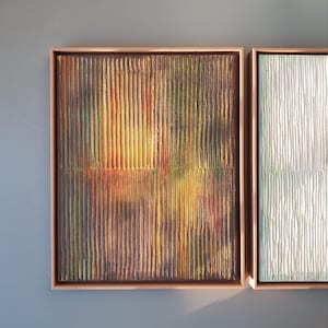 Può includere: Due dipinti astratti incorniciati con pennellate verticali. Il dipinto a sinistra è un mix di tonalità marroni, gialle, arancioni e verdi. Il dipinto a destra è bianco con sottili sfumature di verde e blu.