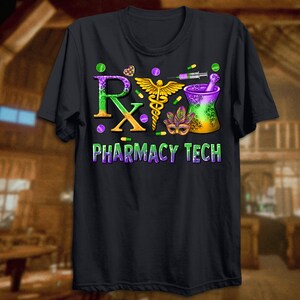 May include: Black t-shirt with a colorful graphic design. The design includes the letters "Rx" in green and orange, a gold caduceus, a mortar and pestle, and the words "PHARMACY TECH" in purple and green. The design also features pills and a syringe.