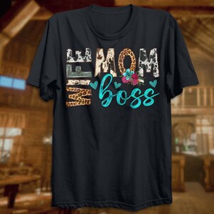 May include: Black t-shirt with a graphic print of "Wife Mom Boss" in turquoise and white lettering with animal print accents and floral details.