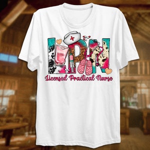 May include: White t-shirt with a colorful graphic design that says "LPN Licensed Practical Nurse". The graphic includes a stethoscope, a nurse's cap, a syringe, a bottle of liquid, and a pair of pink clogs.