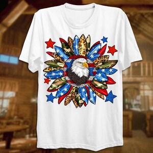 K&ouml;nnte beinhalten: Wei&szlig;es T-Shirt mit einem rot-wei&szlig;-blauen patriotischen Design mit einem Wei&szlig;kopfseeadler in der Mitte. Das Design enth&auml;lt Sterne, Tarnmuster und Leopardenmuster.