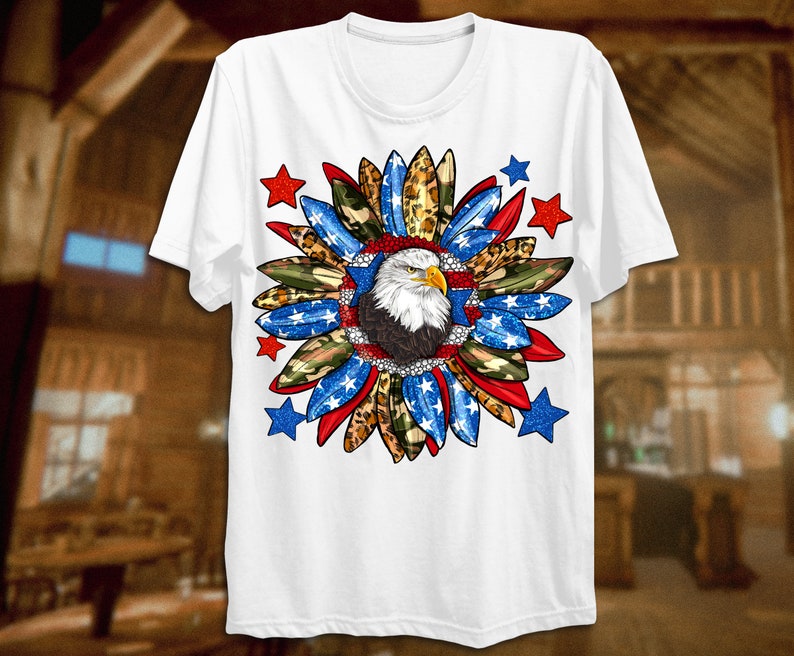 K&ouml;nnte beinhalten: Wei&szlig;es T-Shirt mit einem rot-wei&szlig;-blauen patriotischen Design mit einem Wei&szlig;kopfseeadler in der Mitte. Das Design enth&auml;lt Sterne, Tarnmuster und Leopardenmuster.