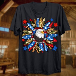 K&ouml;nnte beinhalten: Ein schwarzes T-Shirt mit einem Aufdruck eines Wei&szlig;kopfseeadlers in einem rot-wei&szlig;-blauen Sternendesign. Der Adler ist von Tarnung, Leopardenmuster und Federn umgeben.