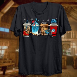 May include: Black t-shirt with a graphic of five different beverages, including a coffee, iced coffee, slushie, and two beers. The graphic also includes a hockey stick and a hockey skate.