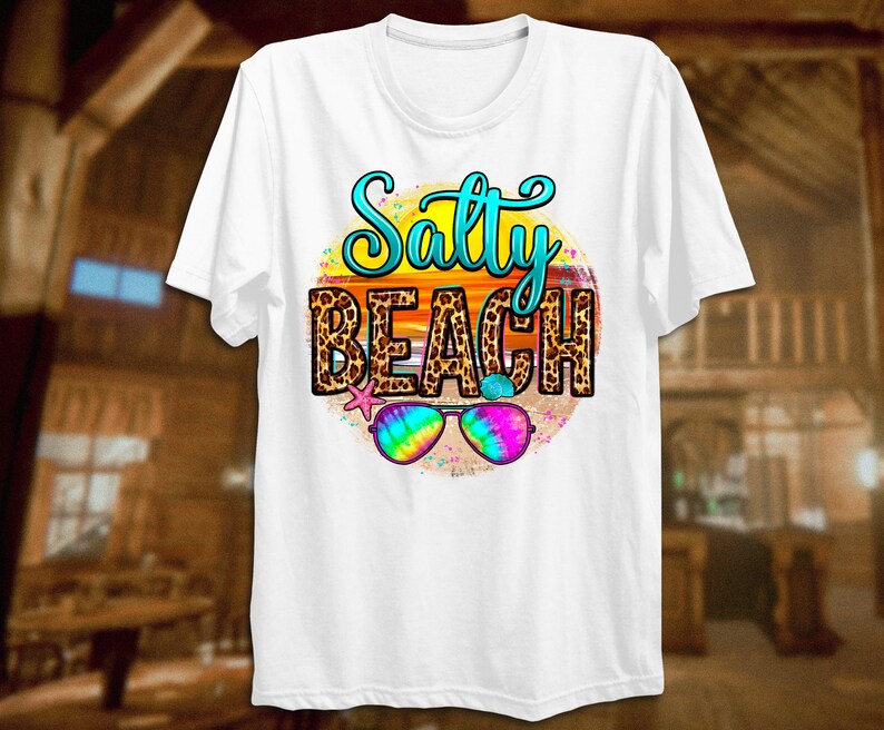 May include: White t-shirt with a graphic of a sunset with a leopard print design and the text "Salty Beach". Sunglasses are in front of the sunset.
