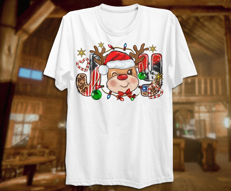 Pu&ograve; includere: Maglietta bianca con un design natalizio che presenta una renna dei cartoni animati con un cappello di Babbo Natale e circondata da bastoncini di zucchero, luci e una stampa leopardata. La parola "JOY" &egrave; scritta con la testa della renna al centro.