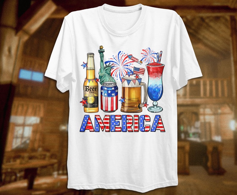 May include: White t-shirt with a red, white, and blue American flag design. The design features a beer bottle, a can of beer, a beer mug, a cocktail, and fireworks. The text "AMERICA" is written in red, white, and blue letters.