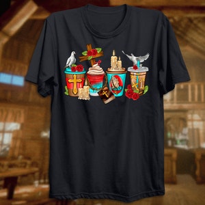 Puede incluir: Una camiseta negra con un dise&ntilde;o gr&aacute;fico de cuatro tazas de caf&eacute; con im&aacute;genes religiosas. Cada taza tiene una cruz, una paloma, una vela y una biblia. Las tazas est&aacute;n rodeadas de rosas rojas.