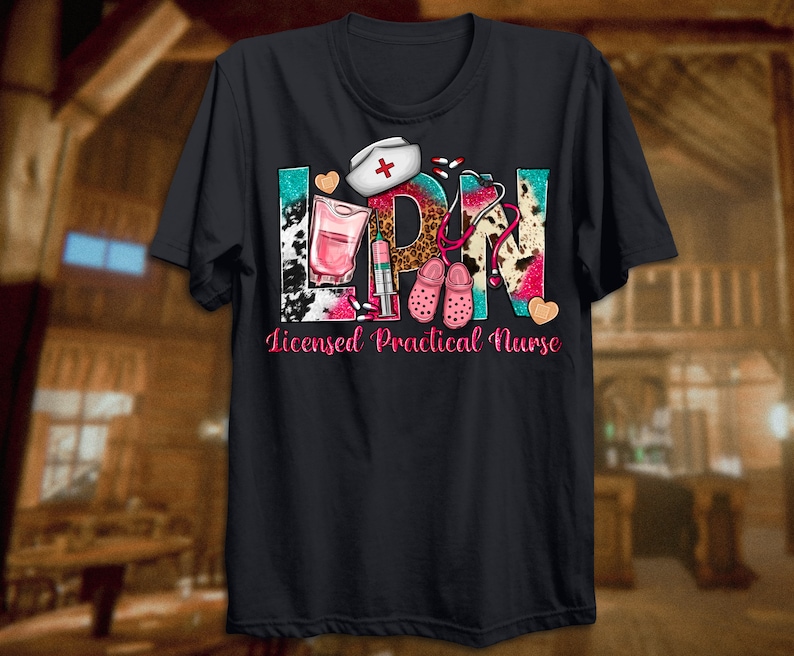 May include: Black t-shirt with a colorful graphic design that says "LPN" with a stethoscope, pills, a nurse's hat, and a pair of pink clogs. The text below the graphic says "Licensed Practical Nurse".