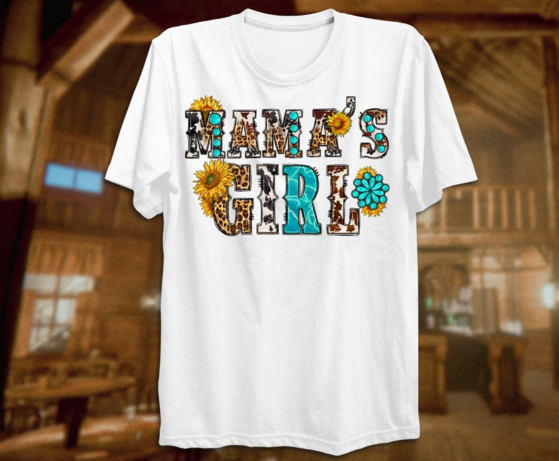 May include: White t-shirt with the text "Mama's Girl" in colorful letters with a cowhide, leopard print, and sunflower design.