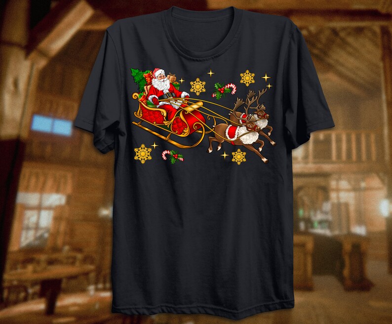 Puede incluir: Una camiseta negra con un dise&ntilde;o navide&ntilde;o que presenta a Pap&aacute; Noel en un trineo tirado por renos. El dise&ntilde;o incluye copos de nieve, bastones de caramelo y acebo.