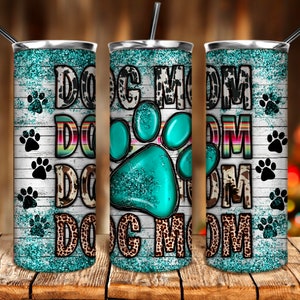 May include: A set of three stainless steel tumblers with a turquoise glitter background and white woodgrain design. The tumblers feature a large turquoise paw print with glitter and the text "Dog Mom" in black and white.