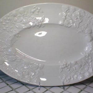 May include: White oval serving platter with raised floral and fruit design.