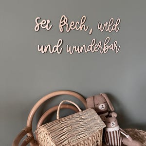 May include: Wooden wall decor with the German phrase "Sei frech, wild und wunderbar" which translates to "Be cheeky, wild and wonderful".