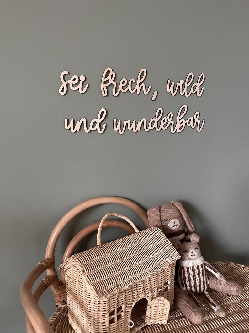 May include: Wooden wall decor with the German phrase "Sei frech, wild und wunderbar" which translates to "Be cheeky, wild and wonderful".