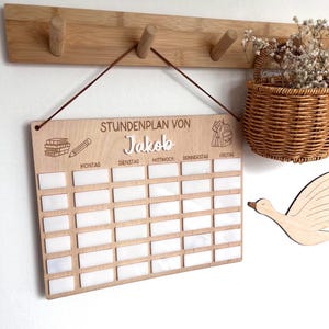 Puede incluir: Un tablero de horario de madera con cuadrados blancos para escribir. El tablero tiene el texto "STUNDENPLAN VON Jakob" en la parte superior y los días de la semana etiquetados debajo.