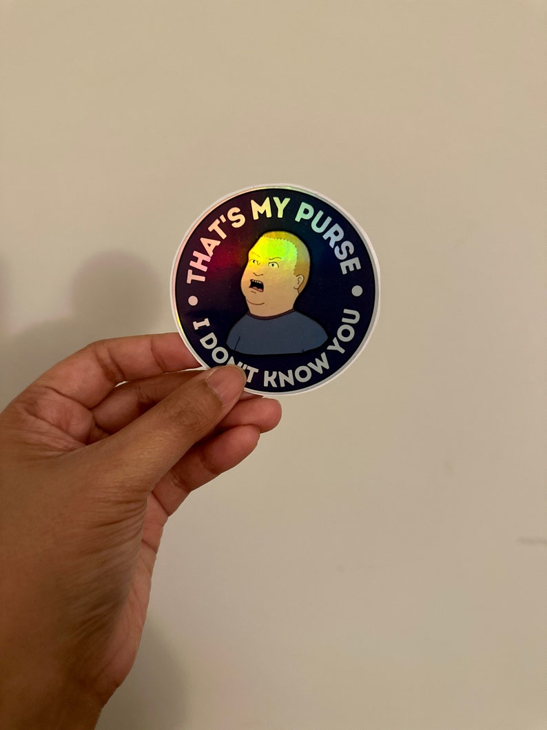May include: A round sticker with a holographic finish features a cartoon character with a surprised expression. The sticker has the text "That's my purse. I don't know you."