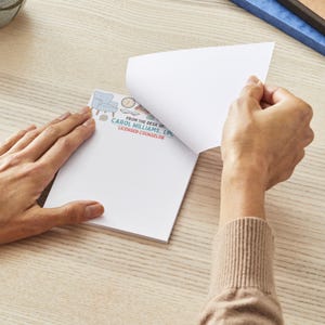 May include: A white notepad with a light blue header featuring a chair, clock, and other small illustrations. The text "FROM THE DESK OF CAROL WILLIAMS, LPC LICENSED COUNSELOR" is printed on the notepad. A person is shown peeling back a page.