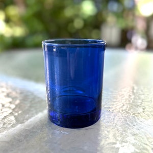 May include: A cobalt blue glass shot glass with a rounded bottom and a smooth, clear surface.