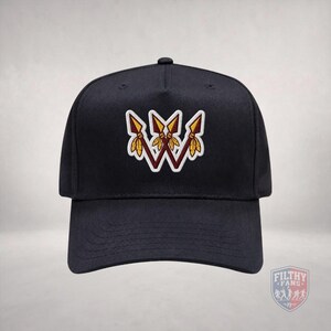 May include: A black baseball cap featuring an embroidered design of three crossed spears in maroon and gold with yellow feathers. The spears are arranged to form a W shape with a white outline. A small logo with the text FILTHY FANS is visible.