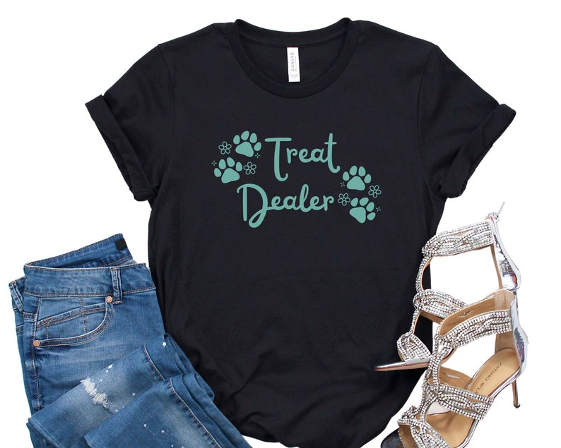May include: Black t-shirt with the text "Treat Dealer" in teal green lettering and paw print graphics.