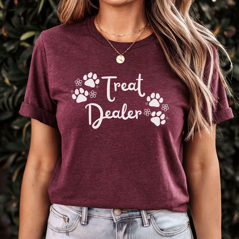 May include: A maroon t-shirt with white paw prints and the text "Treat Dealer" printed on the front.