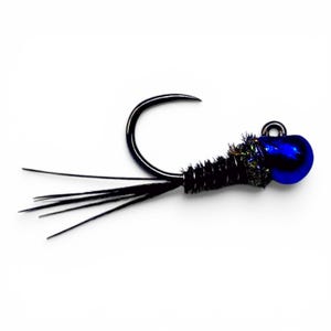 Pode incluir: Uma mosca de pesca com um anzol de metal preto curvo, uma cabeça de conta azul metálico brilhante e um corpo enrolado em fio preto com fibras iridescentes. A cauda consiste em vários filamentos pretos finos e retos.