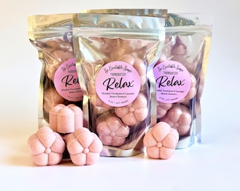 May include: Three silver pouches filled with pink flower-shaped shower steamers. The pouches have labels that say "So Excitable Soaps Handcrafted Relax Menthol, Eucalyptus & Lavender Shower Steamers 8 oz / 227 grams".