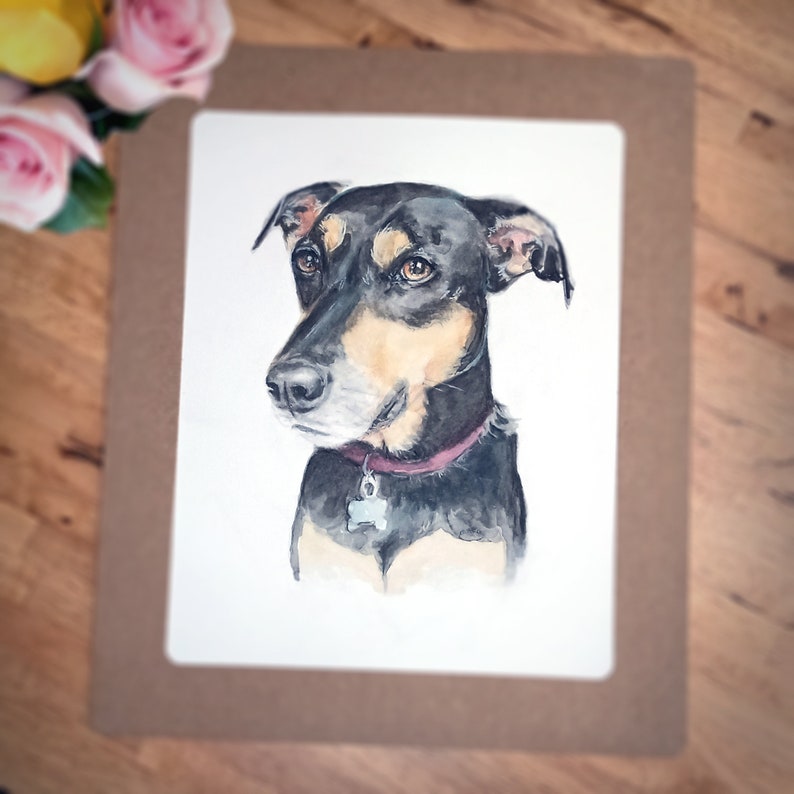 May include: Watercolor painting of a black and tan dog with a pink collar and a tag. The dog is looking to the left of the image.