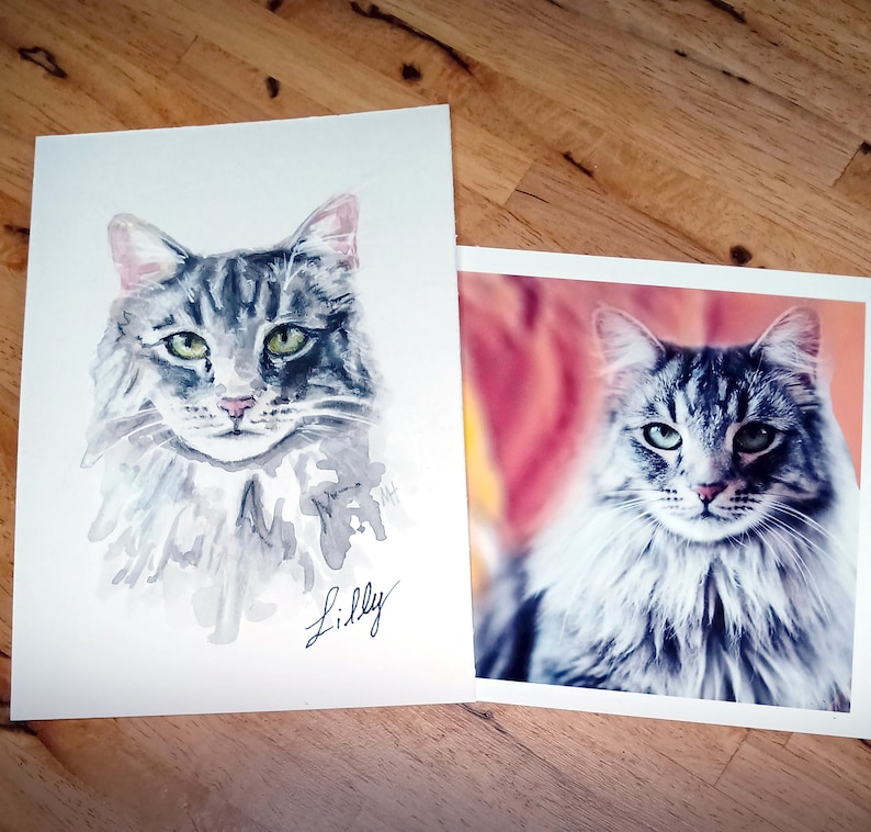 May include: A watercolor painting of a gray and white cat with green eyes. The cat is looking directly at the viewer. The painting is signed "Lilly".