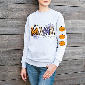 Pode incluir: Camisola cinzenta com o texto "This Mama loves her pumpkins" e tr&ecirc;s ab&oacute;boras laranja com a palavra "Name" em cada uma.