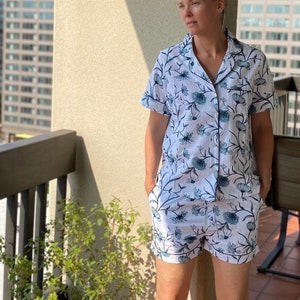 May include: A white and blue floral print pajama set with short sleeves and shorts. The top has a button-up closure and a collar.