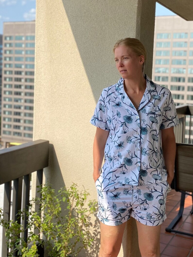 May include: A white and blue floral print pajama set with short sleeves and shorts. The top has a button-up closure and a collar.