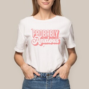 K&ouml;nnte beinhalten: Wei&szlig;es T-Shirt mit einer pinkfarbenen Grafik, auf der in einer Retro-Schrift "Probably Anxious" steht.