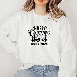 Puede incluir: Sudadera blanca con texto negro que dice "Happy Campers" con una silueta de autocaravana y pinos. El texto "FAMILY NAME" est&aacute; debajo del gr&aacute;fico.