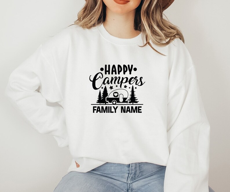 Puede incluir: Sudadera blanca con texto negro que dice "Happy Campers" con una silueta de autocaravana y pinos. El texto "FAMILY NAME" est&aacute; debajo del gr&aacute;fico.
