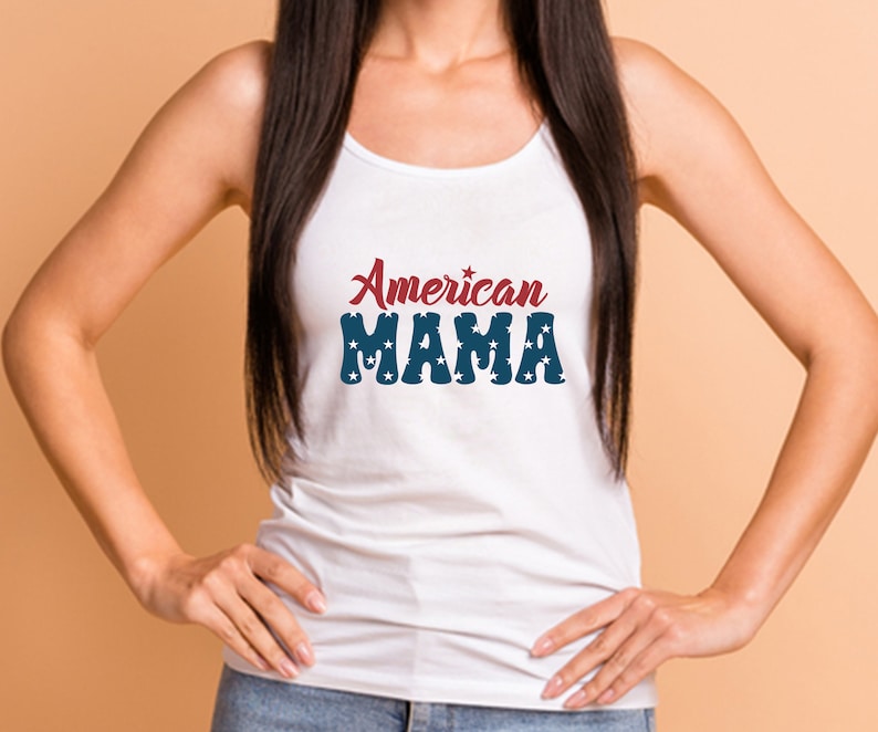 May include: White tank top with the text "American MAMA" in red and blue. The word "American" is in a script font, and "MAMA" is in a block font with star accents. The top is a casual style.