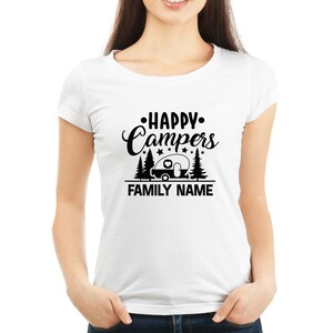 Puede incluir: Camiseta blanca con texto negro que dice "Happy Campers" con una caravana y &aacute;rboles. El texto "FAMILY NAME" est&aacute; debajo del gr&aacute;fico.