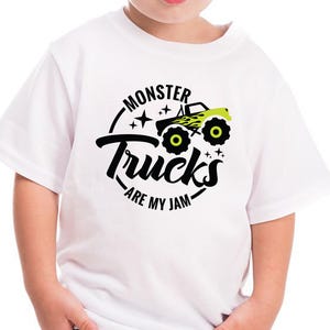 Może przedstawiać: Biała koszulka z czarnym i zielonym nadrukiem monster trucka i tekstem "Monster Trucks Are My Jam".