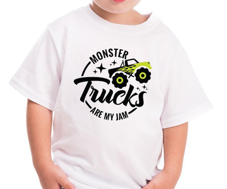 Może przedstawiać: Biała koszulka z czarnym i zielonym nadrukiem monster trucka i tekstem "Monster Trucks Are My Jam".