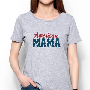 May include: A light gray t-shirt with the text "American MAMA" in red and blue. The word "American" is in a script font, and "MAMA" is in a block font with white stars.